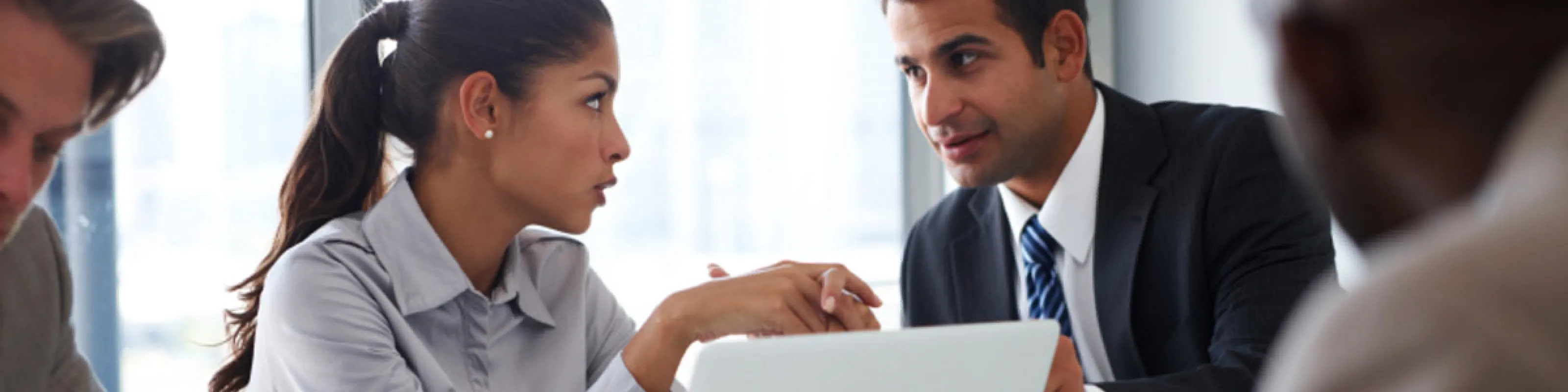Two business people making eye contact over a laptop.